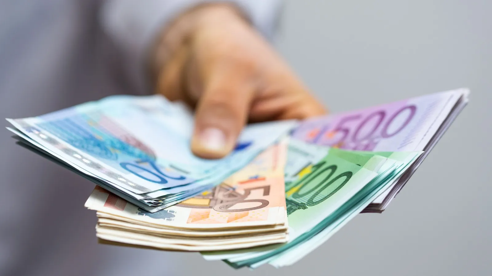 Mann hält diverse Euro-Banknoten in der Hand